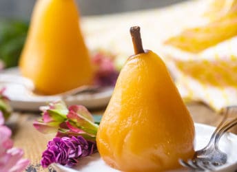 Poached pears served on small ceramic plates with pink flowers.