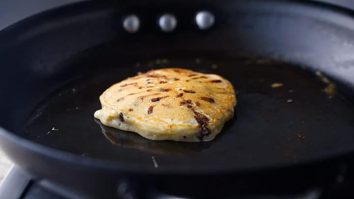 Cooking chocolate chip pancakes until golden brown.