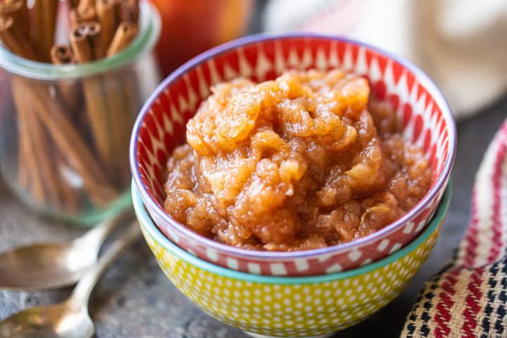 Easy homemade applesauce with cinnamon sticks in the background.