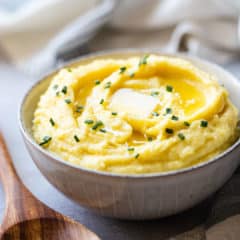 Make-ahead mashed potatoes served in a stoneware bowl with butter.