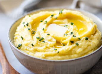 Make-ahead mashed potatoes served in a stoneware bowl with butter.