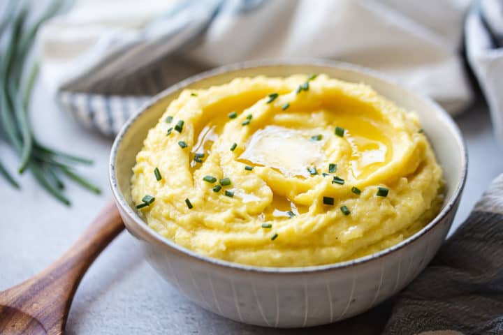 Buttery mashed potatoes in a serving bowl with a wooden spoon.