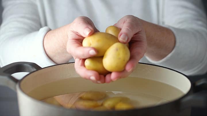 Placing potatoes in a large pot of cold, salted water.