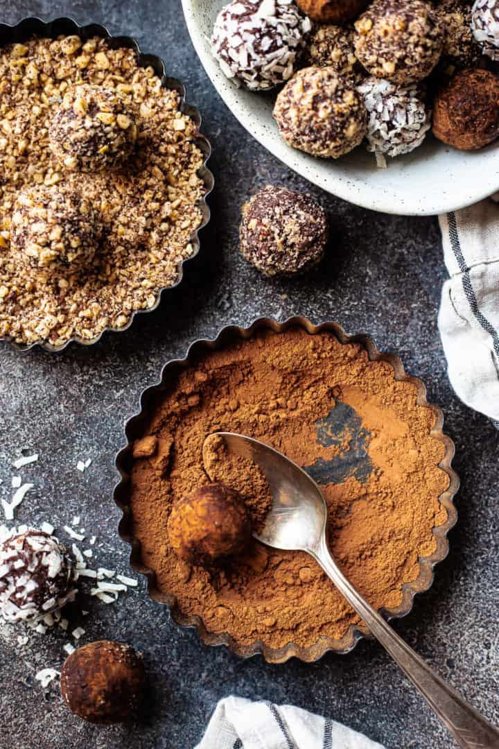 Coating chocolate truffles in cocoa and chopped nuts.