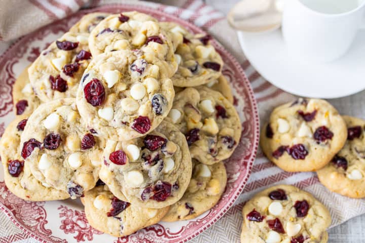 Cranberry orange cookies on a printed red and white plate with a striped cloth.
