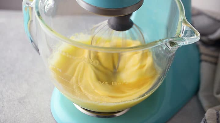Whipping eggs and sugar together until pale, fluffy, and thick.