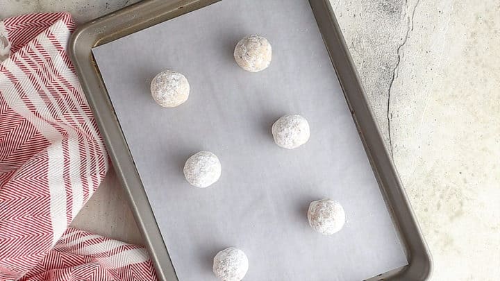 Unbaked Mexican wedding cookies on a baking sheet.