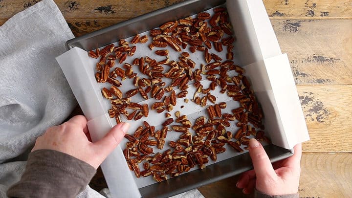 Placing pecans in an even layer to toast in the oven.