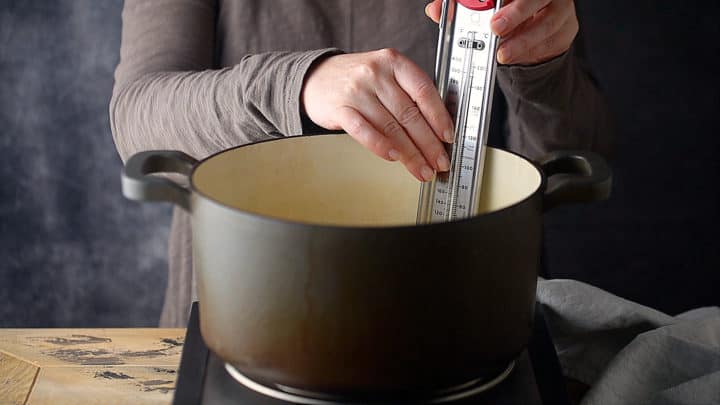 Clipping a candy thermometer to the side of a pot.