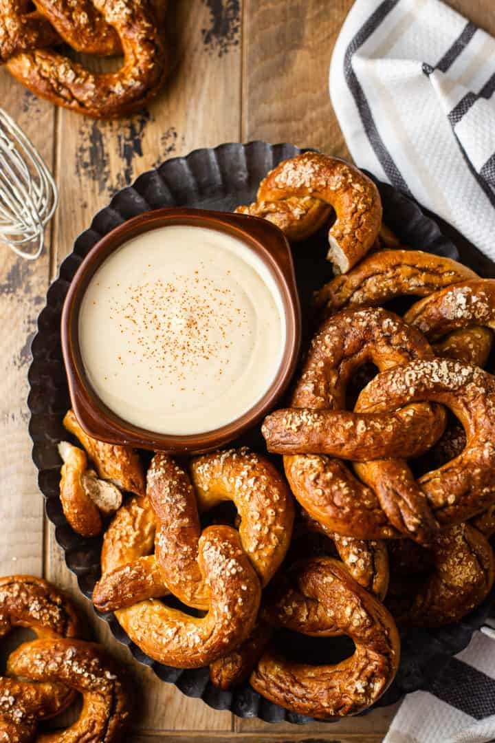 Overhead image of beer cheese recipe, prepared and served in a brown bowl and surrounded with soft pretzels.