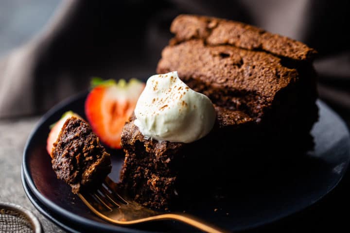 Closeup image of best flourless chocolate cake recipe, with one bite on the fork showing the moist, fudgy texture.