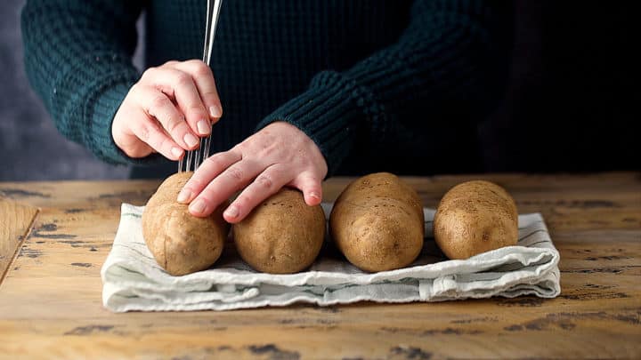 Pricking potatoes with a fork.