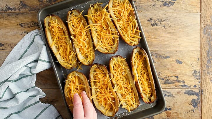 Filling potato skins with shredded cheese.