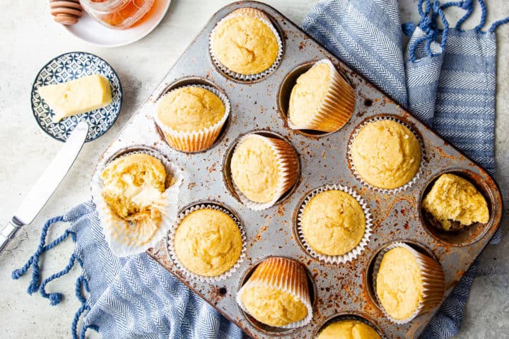 Cornbread muffin recipe, prepared and arranged on a blue towel with soft butter and honey.