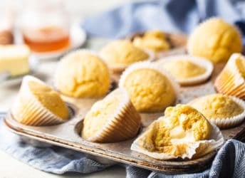 Cornbread muffins in a vintage muffin tin with a blue kitchen towel.