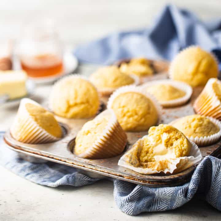 Cornbread muffins in a vintage muffin tin with a blue kitchen towel.