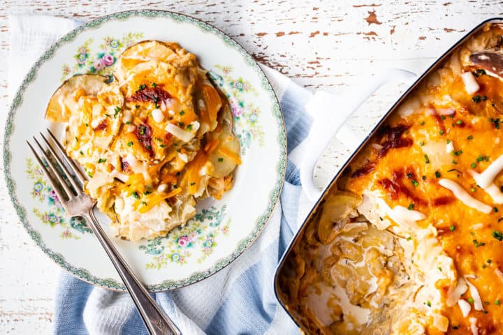 Au gratin potatoes recipe in a baking dish with an individual serving on a vintage plate.