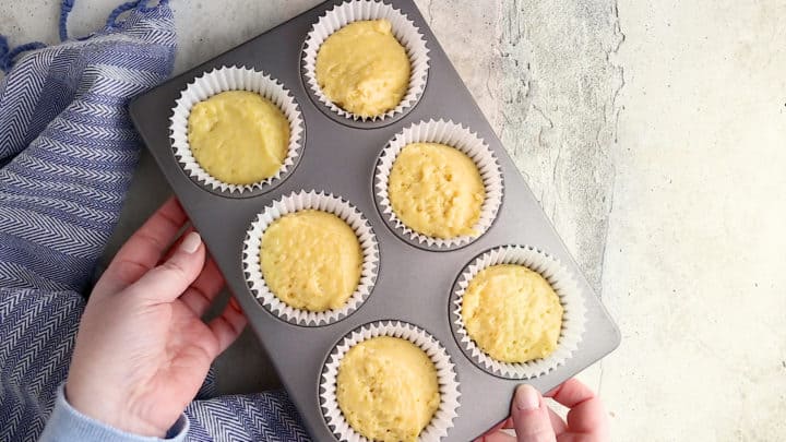 Unbaked corn muffins in a pan with paper liners.