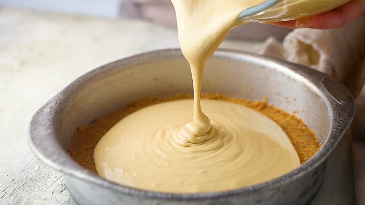 Pouring cheesecake filling over crust.