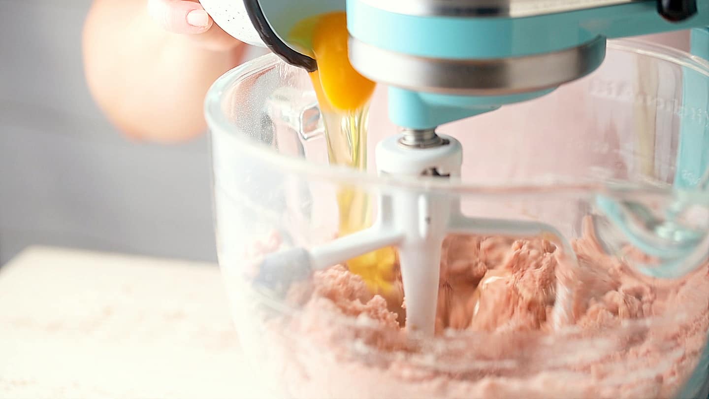 Ajouter les œufs au mélange de gâteau aux fraises.