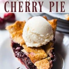 Slice of cherry pie on white plate topped with a scoop of vanilla ice cream.