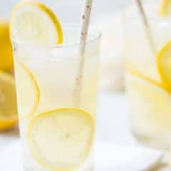 tall glass of lemonade with straw and fresh lemon slices