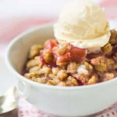 Bowl of rhubarb crisp topped with a scoop of vanilla ice cream.