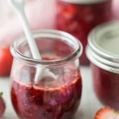 Strawberry jam in glass jar with spoon.