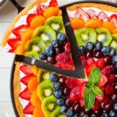 Fruit pizza with slice pulled out.