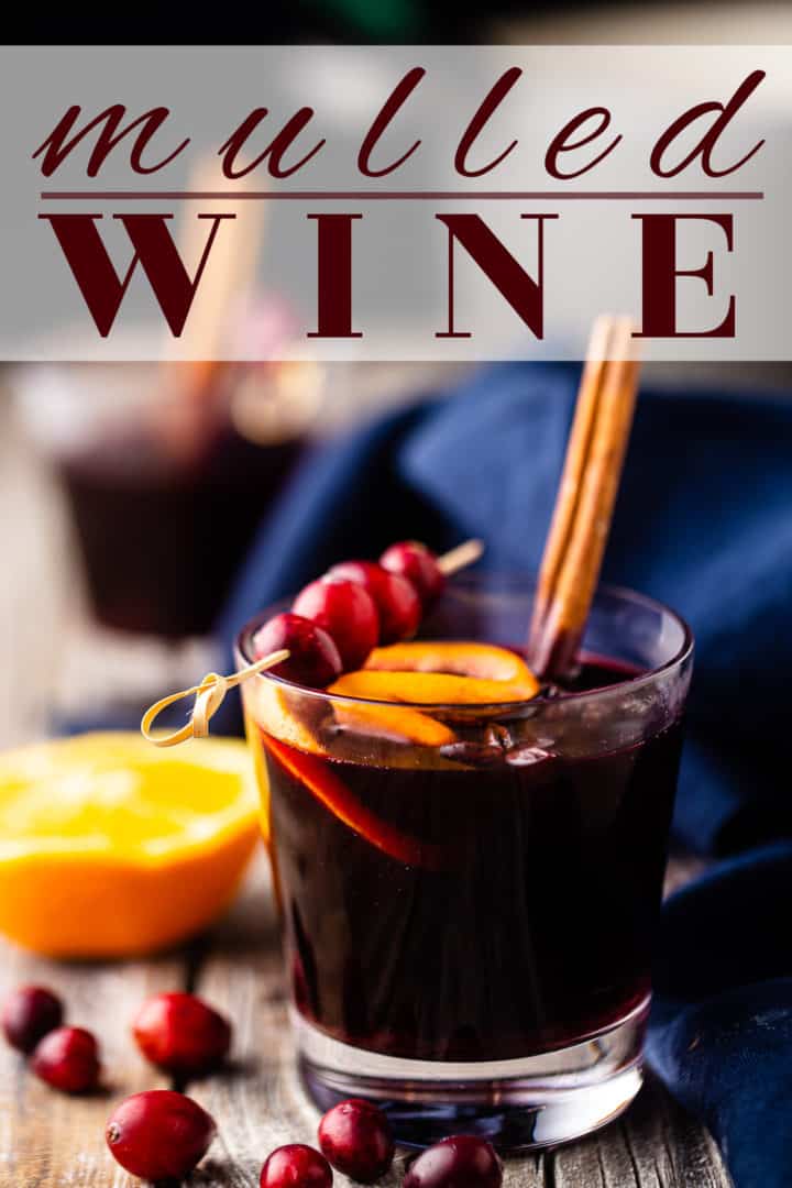Head on image of mulled wine recipe, prepared & garnished with a cinnamon stick, and a text overlay that reads "Mulled Wine."