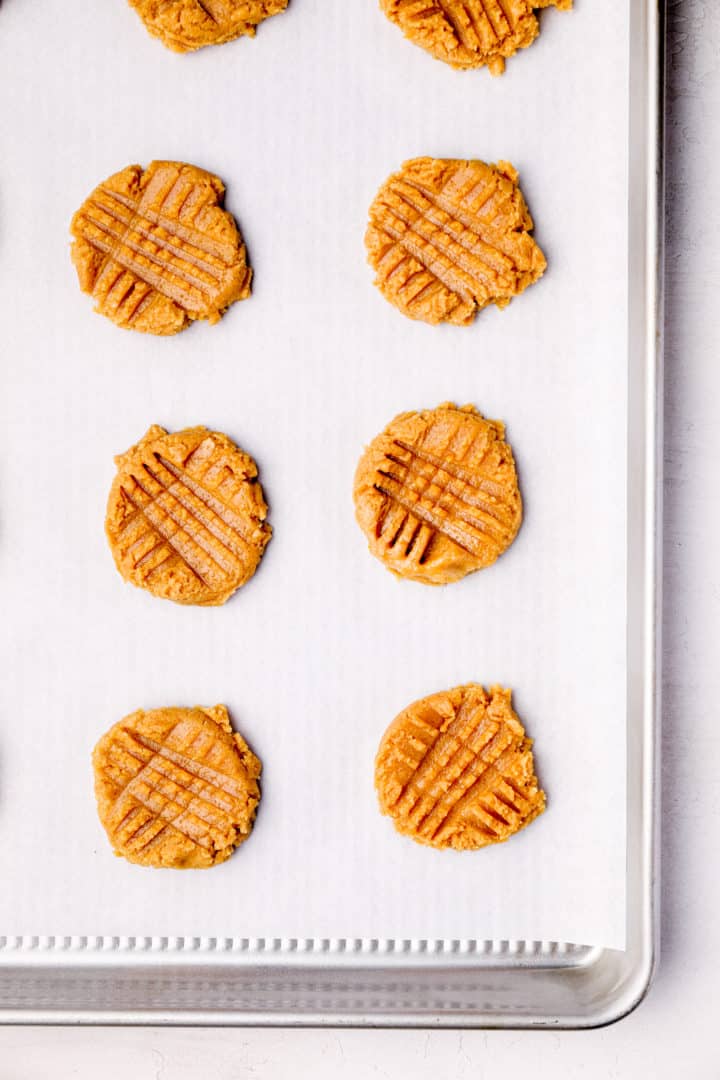 Unbaked peanut butter cookies on a baking sheet.