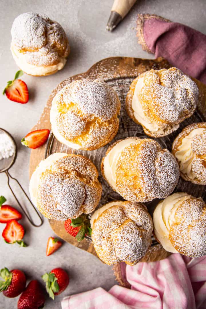 Overhead image of cream puff filling spilling out of pastries with strawberries and powdered sugar.