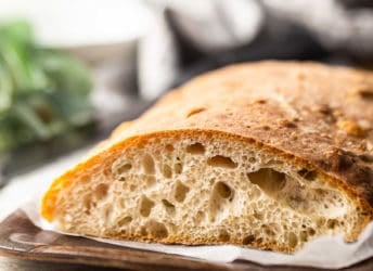 Close up image of the cut end of a loaf of ciabatta, showcasing the light, airy interior.