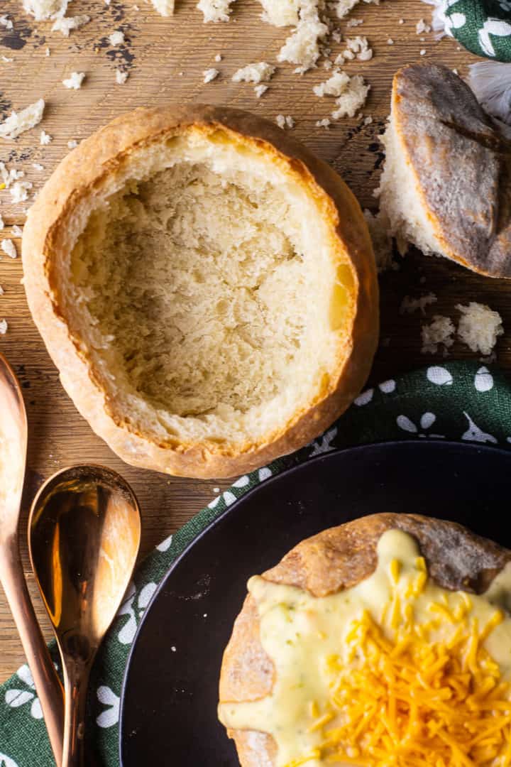 Overhead image of two bread bowls, one filled with soup and the other scooped out and empty.