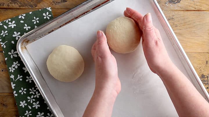 Placing unbaked bread dough on a baking sheet to rise.