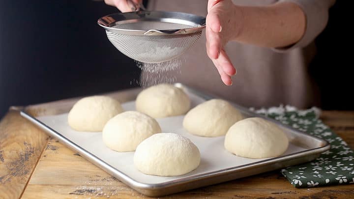 Dusting unbaked bread bowls with flour.