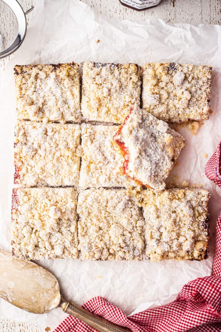 Overhead image of strawberry jam bars recipe, prepared and cut into squares, with a sifter of powdered sugar.