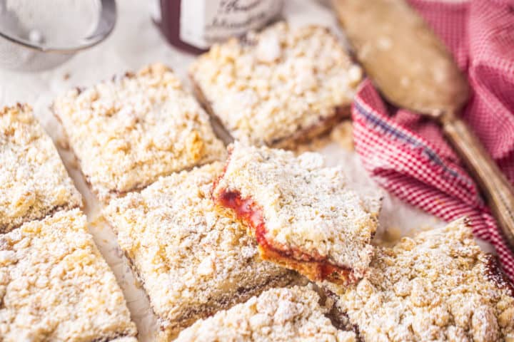 Strawberry jam bar recipe, prepared and served on a sheet of parchment, with a silver cake server.