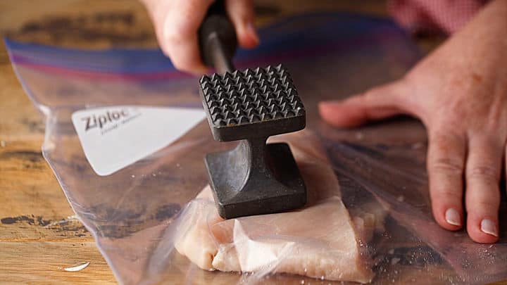 Pounding chicken breasts to even out their thickness.
