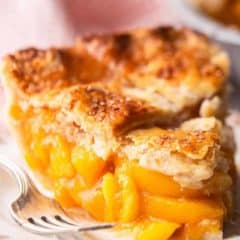 Best peach pie recipe, cut into a slice and served on a china plate with a silver fork.