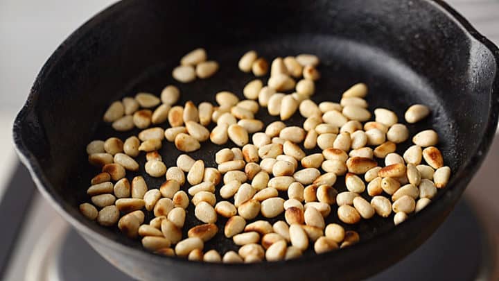 Toasted pine nuts in a cast iron skillet.