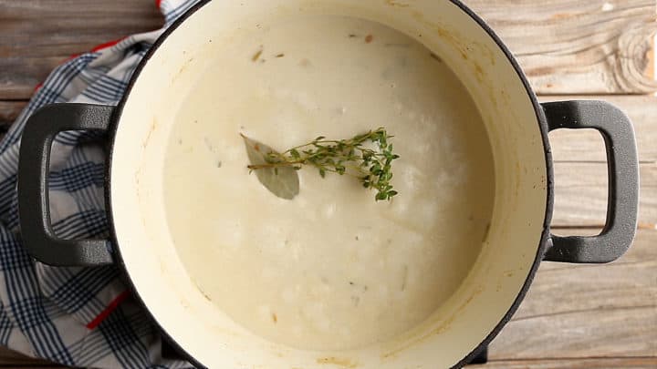 Adding herbs to clam chowder as it cooks.
