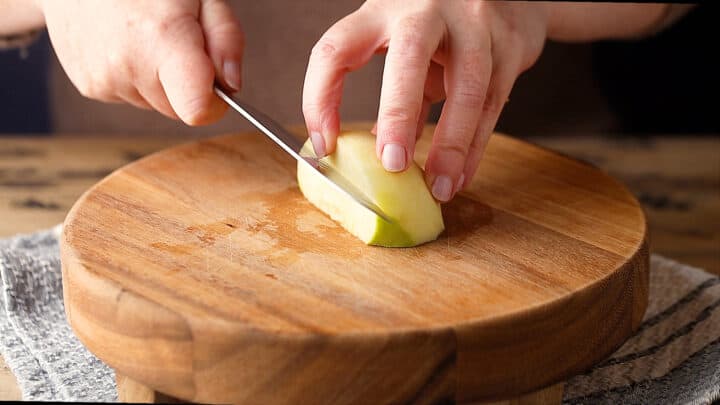 Cutting out the core of a peeled and quartered apple.