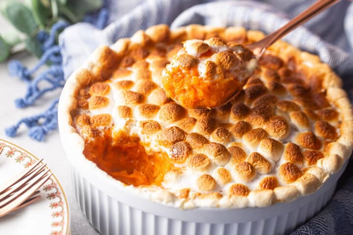 Dishing out a spoonful of sweet potato casserole with marshmallows.