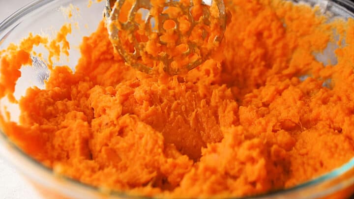 Mashed sweet potatoes in a large glass mixing bowl.