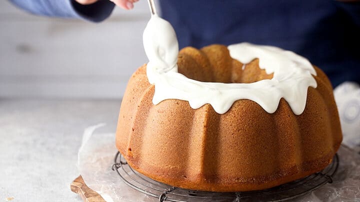 Icing a pumpkin bundt cake with cream cheese glaze.