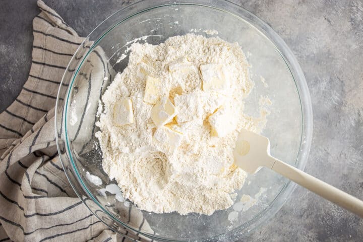Tossing sliced butter in dry ingredients.