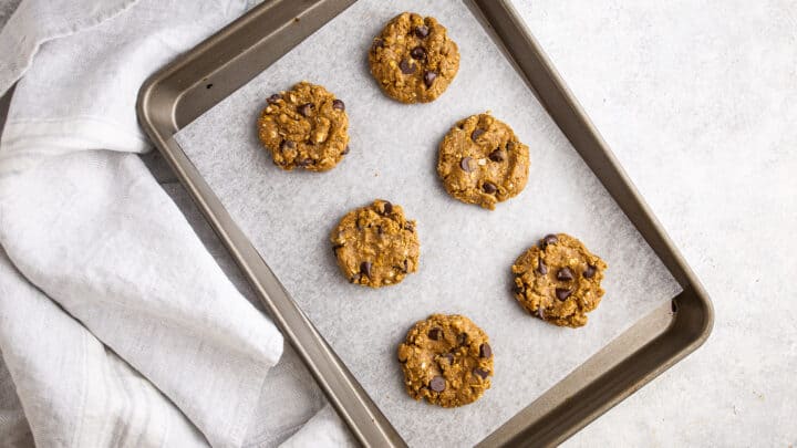 Unbaked protein cookies on a parchment-lined baking sheet.