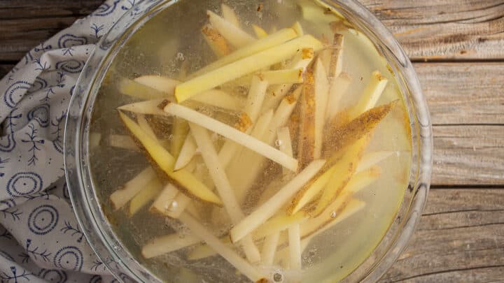 Soaking fries in hot salted and acidulated water.