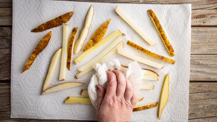Blotting fries dry with clean towels.